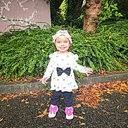 Emmie participe au concours pour gagner de l'argent avec cette photo : child, toddler, girl, smiling, headband, big_bow, pink_bows, shoes, standing, outdoor, leaves, pavement, greenery, tree, shrubs, dress, long_sleeves, black_pants, happy, portrait