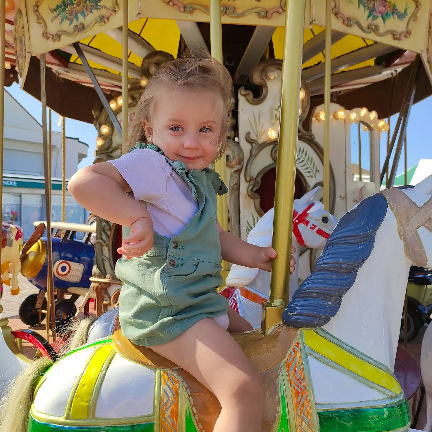 Lyana a rejoint le concours — aidez-le/la à gagner de superbes lots ! amusement_park, amusement_ride, bridle, carousel, child, event, fun, happy, horse, horse_tack, leisure, nonbuilding_structure, person, photograph, playground, recreation, riding_toy, smile, snapshot, toddler