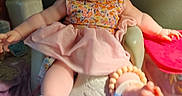 Winter is registered to the contest to win money with this photo: baby, child, smiling, headband, flower, dress, seat, toy, footwear, colorful, happy, indoor, person, infant, cheerful, playful, arms_outstretched, face, cute, accessory
