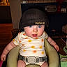 Winter is registered to the contest to win money with this photo: baby, infant, child, blue_eyes, hat, clothing, onesie, sun_pattern, baby_seat, indoor, furniture, face, person, cute, chubby_cheeks, expression, seat_belt, curious, light, home