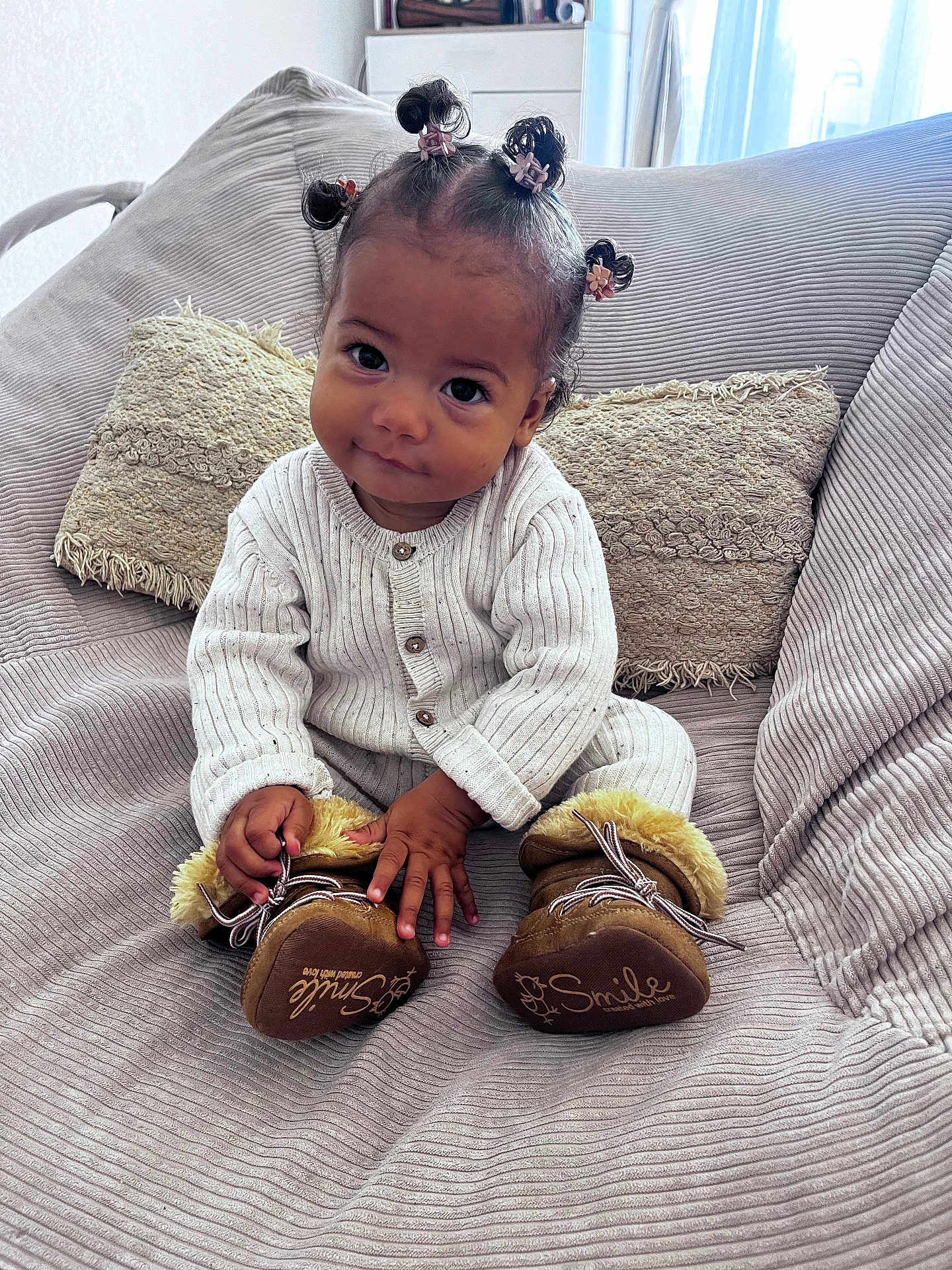 Aliyah participe au concours pour gagner de l'argent avec cette photo : toddler, child, baby, sitting, couch, cushion, knitted_clothing, boots, hair_buns, indoor, portrait, cute, smile, furniture, cozy, soft_lighting, person, home, expression, young_child