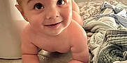 Caden is registered to the contest to win money with this photo: baby, child, tummy, floor, tiled_floor, smile, curious, towel, rug, indoors, person, skin, hands, wide_eyes, head, hair, home, door, hallway, cozy