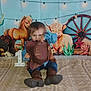 Romeo is registered to the contest to win money with this photo: child, cowboy, hat, boots, blanket, western_theme, horse, steer, wagon_wheel, cactus, string_lights, props, rustic, indoor, portrait, smiling, costume, decor, playful, shy