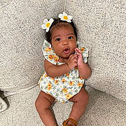 Oaklynn joined the competition — help win amazing prizes! baby, child, girl, flower_hairclip, sitting, couch, floral_dress, sandals, clapping, expression, indoors, cute, happy, person, skin, hand, footwear, texture, comfortable, portrait