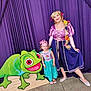 Aubrey is registered to the contest to win money with this photo: child, woman, princess_costume, rapunzel_costume, purple_curtain, cartoon_chameleon, smiling, dress, costume, flower_hair, braided_hair, indoor, floor, footwear, posing, celebration, happy, portrait, event, fun