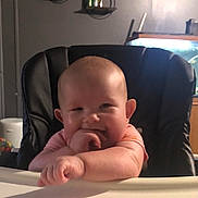 Lilith is registered to the contest to win money with this photo: baby, high_chair, infant, smiling, hand, face, arm, furniture, indoor, person, child, cute, home, sitting, skin, head, expression, room, background, lighting