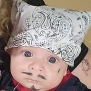 Gaby is registered to the contest to win money with this photo: baby, bandana, face_paint, mustache, goatee, blue_eyes, curly_hair, tattoo, red_clothing, black_clothing, portrait, indoor, person, cute, infant, headwear, expression, closeup, human, child