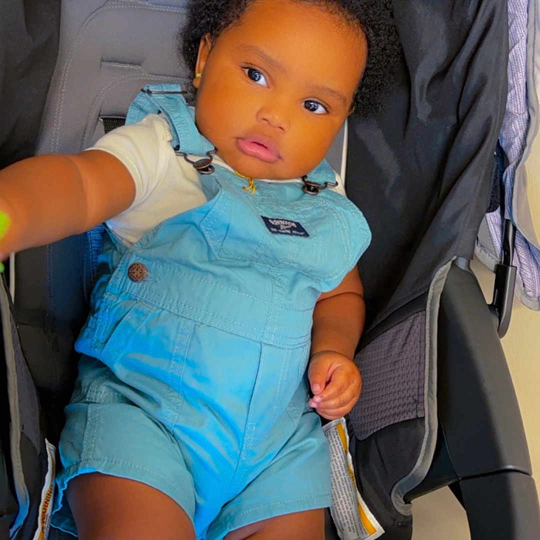 Khayri Gianni is registered to the contest to win money with this photo: accessories, baby, bed, clothing, cushion, face, footwear, furniture, happy, head, homedecor, person, photography, portrait, shorts, sitting, smile, stroller, sunglasses, toy