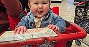 Ella participe au concours pour gagner de l'argent avec cette photo : baby, shopping_cart, store, child, tongue_out, denim_jacket, floral_pants, playful, indoor, person, floor_tiles, shopping, people, casual_clothing, footwear, retail, smiling, cute, red, fun