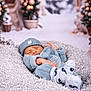 baby, blue_clothing, blurred_background, christmas_trees, cozy, cushion, decor, festive, hat, holiday, indoor, infant, newborn, peaceful, portrait, resting, sleeping, socks, soft_texture, winter_theme