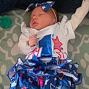 Evelyn is registered to the contest to win money with this photo: newborn, baby, infant, sleeping, headband, clothing, dress, ruffles, blue, red, white, pattern, blanket, pacifier, cute, peaceful, laying, portrait, indoors, child
