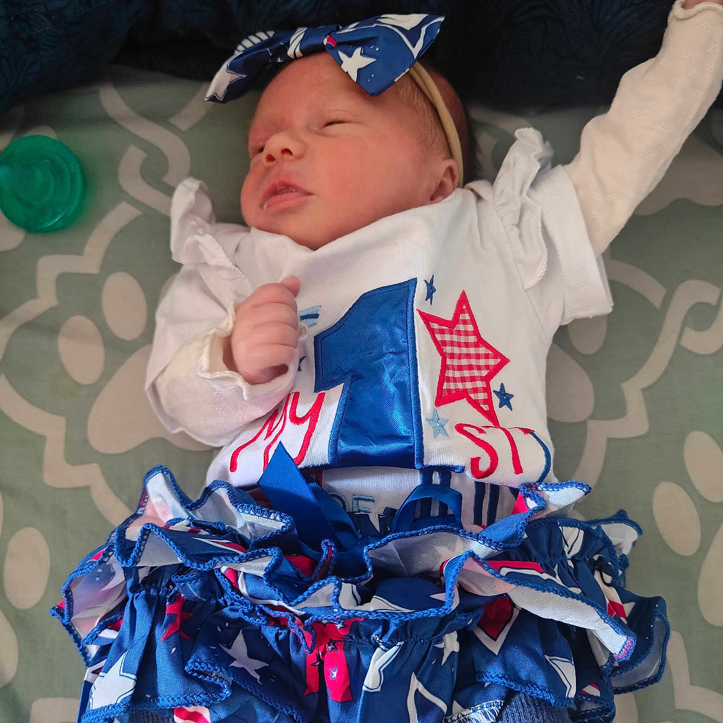 Evelyn is registered to the contest to win money with this photo: newborn, baby, infant, sleeping, headband, clothing, dress, ruffles, blue, red, white, pattern, blanket, pacifier, cute, peaceful, laying, portrait, indoors, child