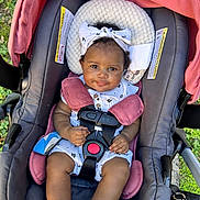 Milani is registered to the contest to win money with this photo: baby, child, stroller, seatbelt, headband, smile, outdoor, greenery, cute, infant, clothing, socks, pink, gray, sitting, portrait, baby_carrier, happy, person, closeup