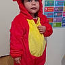 child, costume, dragon, red, yellow, indoors, door, floor, socks, number_chart, educational, cute, portrait, standing, person, clothing, young, baby, face, curious