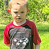 child, boy, party_hat, tshirt, game_controller, outdoor, grass, trees, sunlight, greenery, casual_clothing, short_hair, young, portrait, summer, daytime, nature, standing, expression, birthday