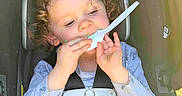 Joyce joined the competition — help win amazing prizes! toddler, child, car_seat, curly_hair, spoon, eating, food, seatbelt, casual_clothing, indoors, baby, hands, face, safety, seat, child_seat, cute, young_child, concentration, plastic_spoon