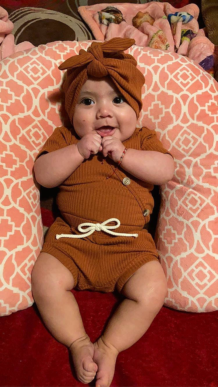 Isela is registered to the contest to win money with this photo: abdomen, baby, baby_toddler_clothing, comfort, eye, facial_expression, happy, head, headwear, human_body, knee, lap, leg, lip, mouth, person, skin, smile, stomach, thigh