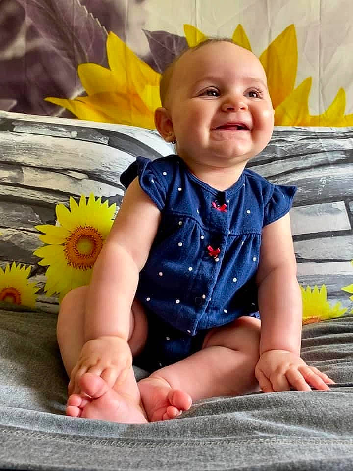 Charlotte is registered to the contest to win money with this photo: baby, child, child_model, flower, hand, happy, joy, leaf, leg, person, photography, plant, sitting, skin, smile, sunflower, toddler, yellow