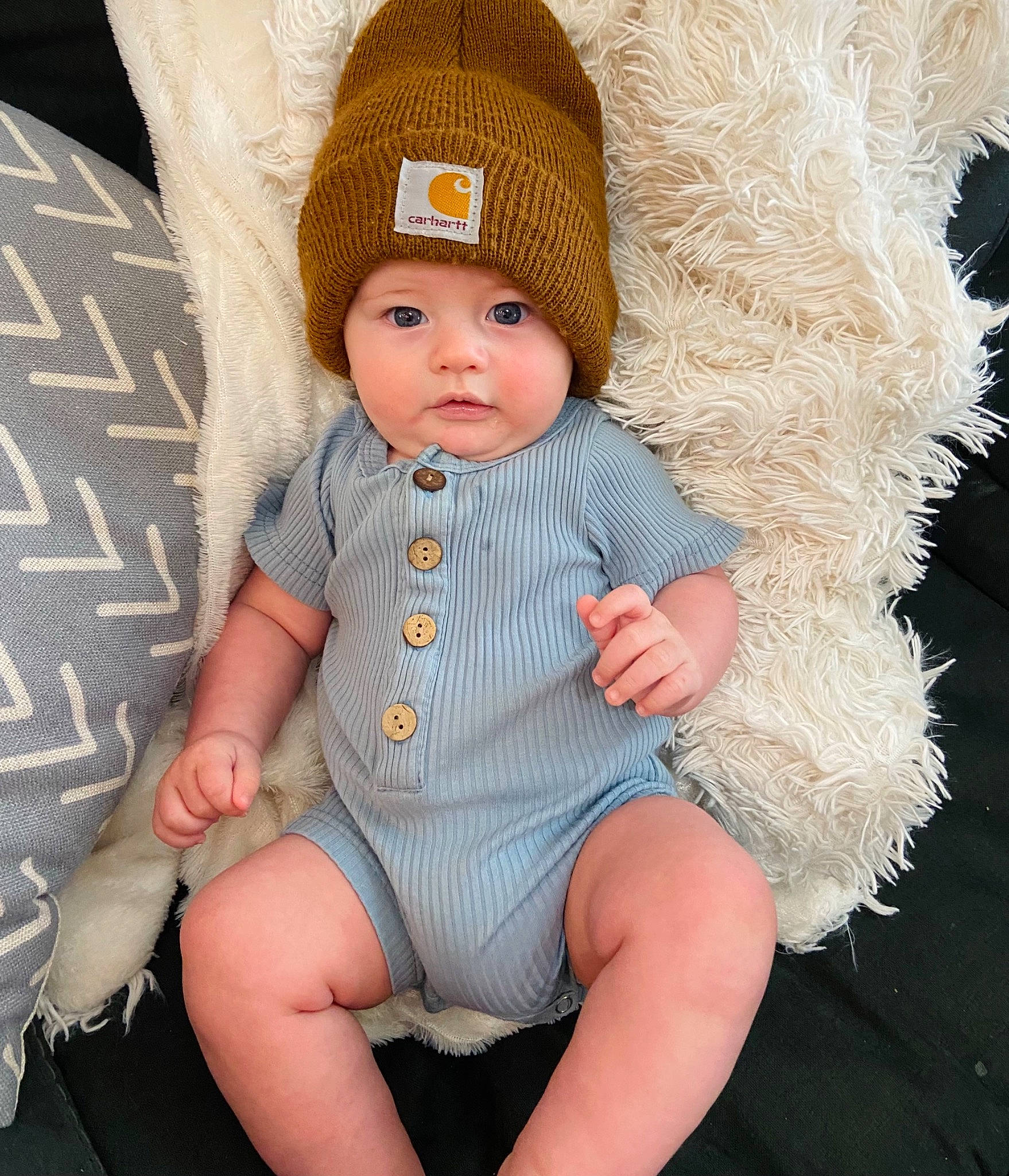 Bentley is registered to the contest to win money with this photo: baby, baby_toddler_clothing, cap, child, costume_hat, eye, fashion_accessory, fur, headwear, human_body, knit_cap, leg, lip, person, sitting, skin, sleeve, textile, thigh, toddler