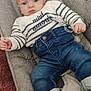 baby, infant, child, sweater, striped_clothing, jeans, socks, pacifier, baby_seat, cushion, carpet, indoor, portrait, clothing, casual, cute, person, young_child, resting, comfortable