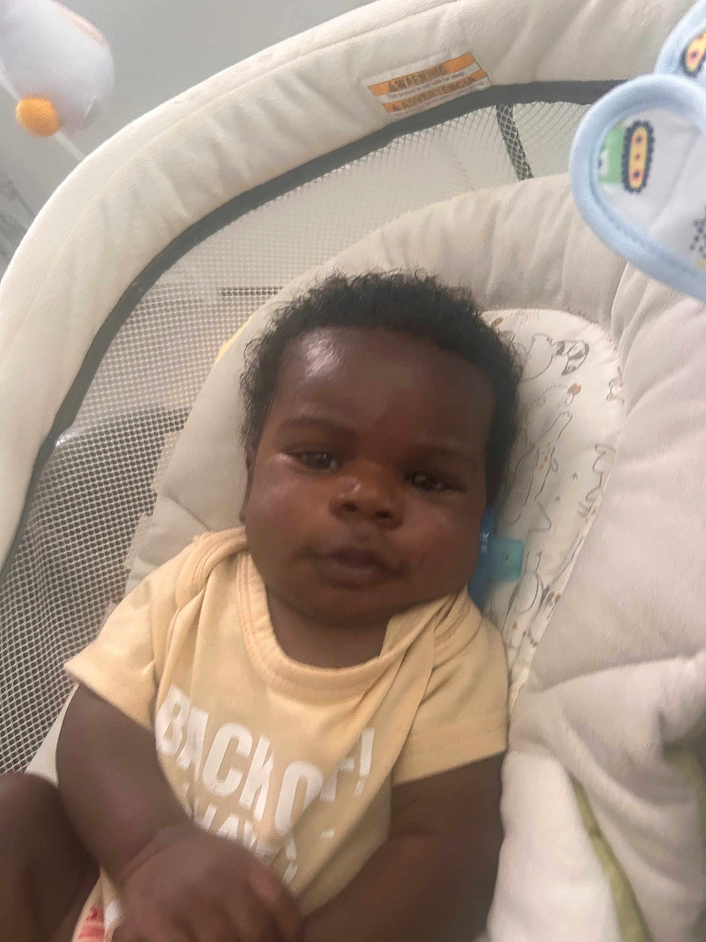 Mar Kail is registered to the contest to win money with this photo: baby, infant, child, face, expression, clothing, shirt, seat, baby_seat, mesh, cushion, plush, indoor, person, skin, hair, portrait, comfort, young, sitting