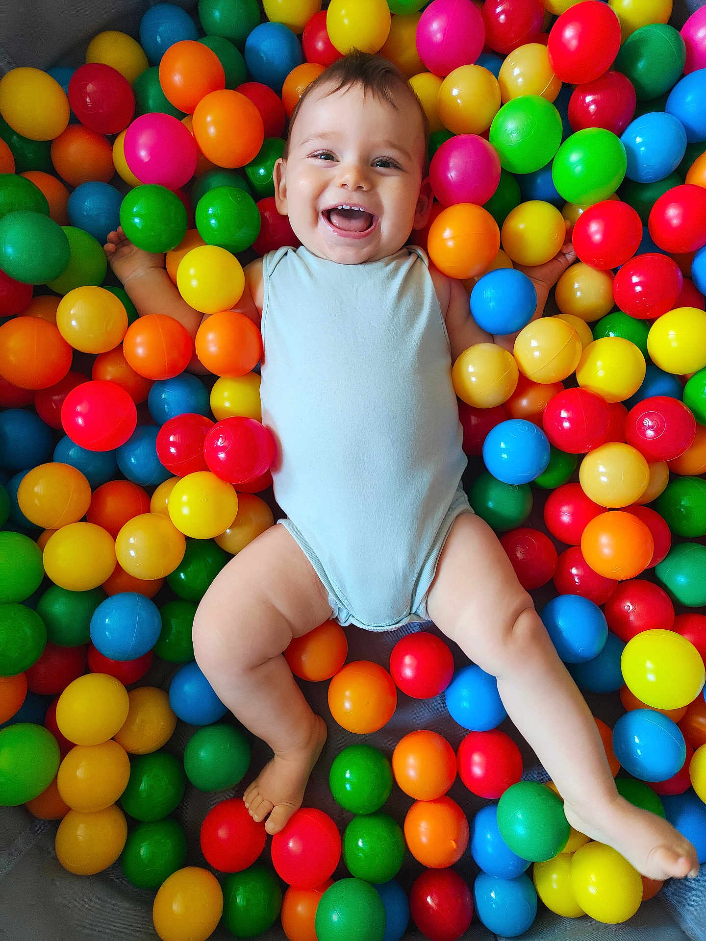 Elyam participe au concours pour gagner de l'argent avec cette photo : baby, child, smiling, happy, colorful, balls, ball_pit, play, fun, cute, infant, one_person, indoors, skin, face, legs, arms, bodysuit, joy, playful