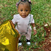 Treasure is registered to the contest to win money with this photo: toddler, child, balloon, golden, star, grass, outdoor, beads, hair, curious, standing, shoes, bracelets, pink, expression, person, casual_clothing, young, nature, daylight