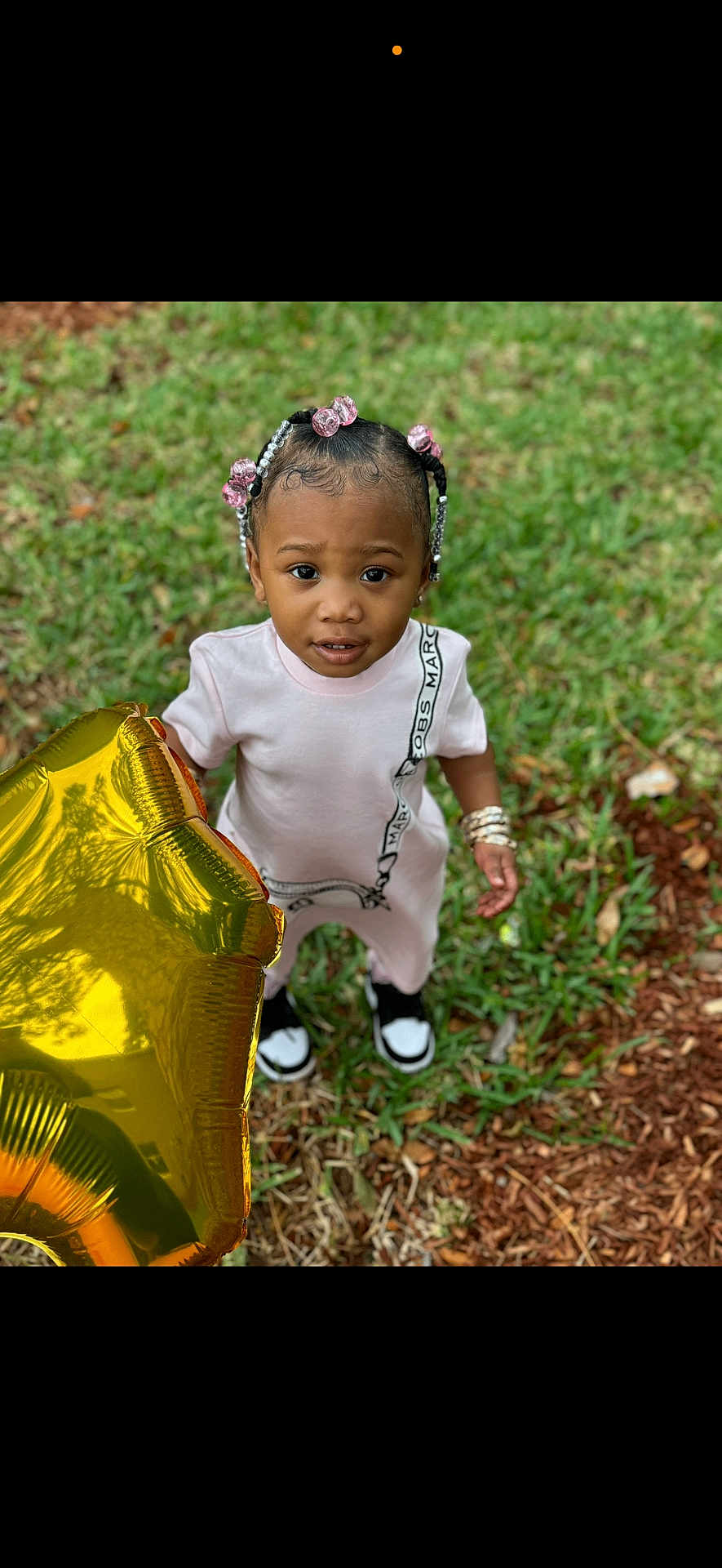 Treasure is registered to the contest to win money with this photo: toddler, child, balloon, golden, star, grass, outdoor, beads, hair, curious, standing, shoes, bracelets, pink, expression, person, casual_clothing, young, nature, daylight