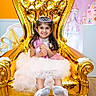 Ariza is registered to the contest to win money with this photo: child, girl, princess, tiara, dress, golden_throne, smile, party, celebration, balloons, birthday_cake, pink, floor, wooden_floor, decorations, happy, portrait, indoor, feet, posing