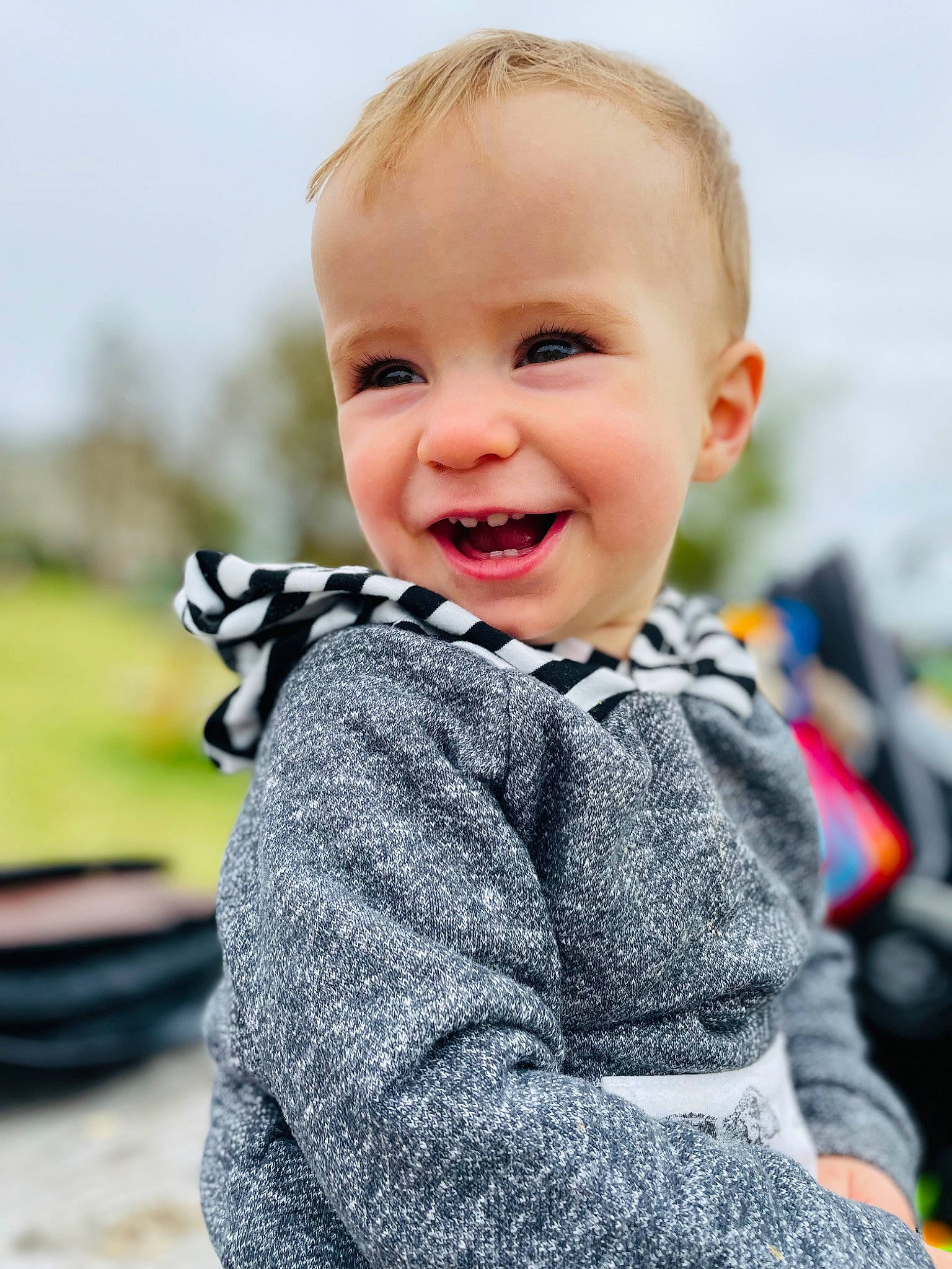 Asher is registered to the contest to win money with this photo: baby, baby_toddler_clothing, child, denim, electric_blue, facial_expression, flash_photography, grass, happy, joy, laugh, pattern, person, portrait_photography, sitting, skin, sky, sleeve, smile, street_fashion
