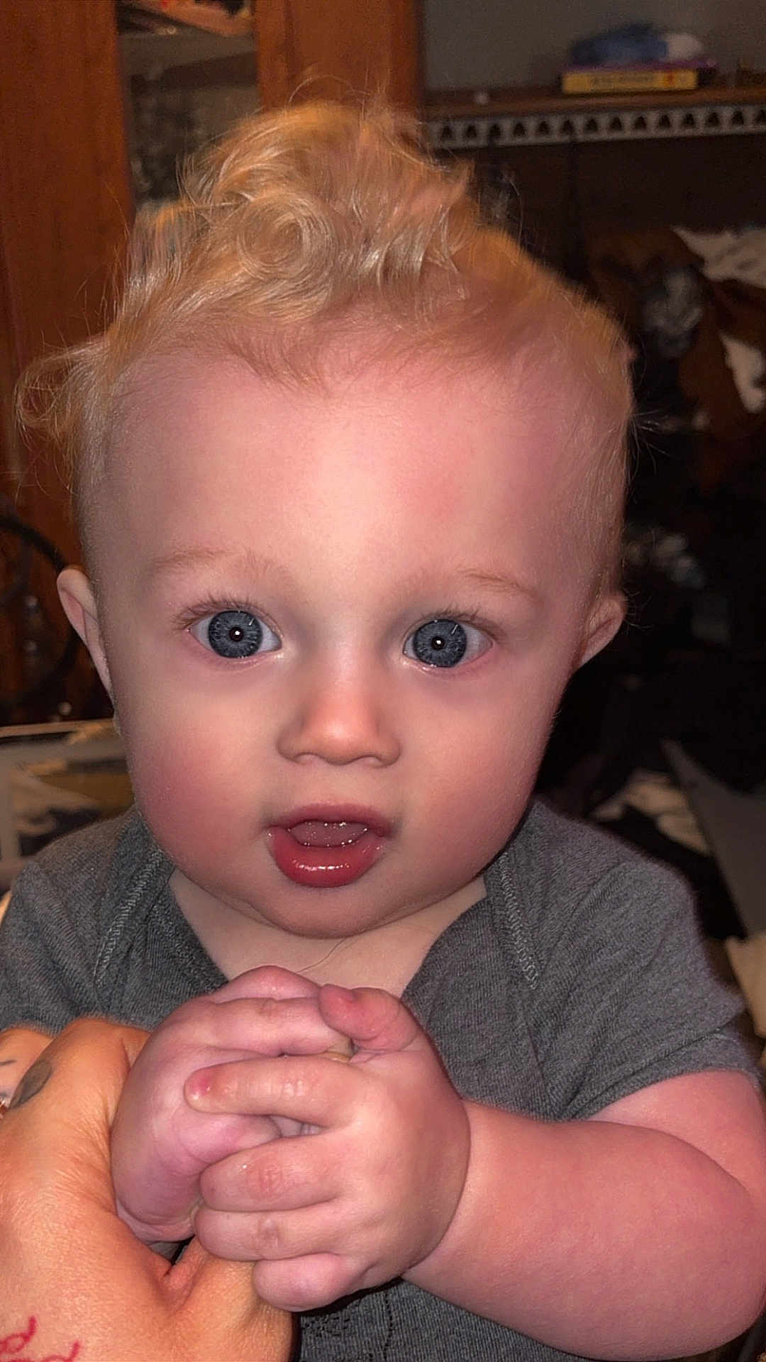 Atreus is registered to the contest to win money with this photo: baby, child, infant, blue_eyes, curly_hair, holding_hands, gray_clothing, indoor, close_up, person, cute, young_child, skin, face, expression, hand, portrait, toddler, human, curious