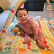 Nilah is registered to the contest to win money with this photo: baby, child, play_mat, onesie, pink_clothing, plush_toy, colorful, animal_prints, indoor, smiling, cute, infant, arch, toy, happy, person, floor_mat, baby_toys, home, child_playing