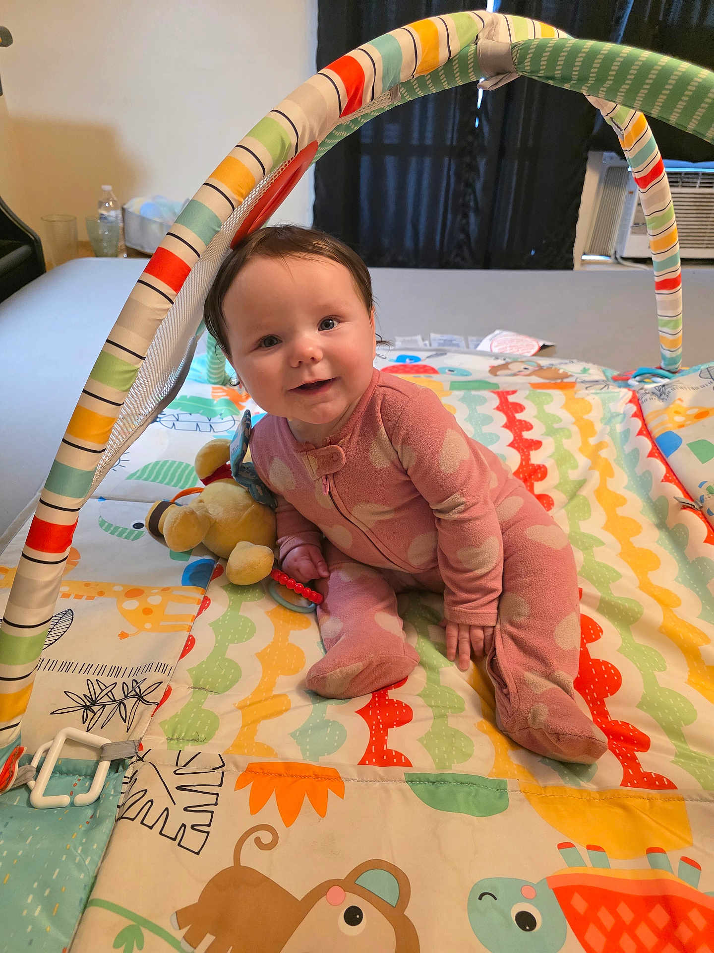 Nilah is registered to the contest to win money with this photo: baby, child, play_mat, onesie, pink_clothing, plush_toy, colorful, animal_prints, indoor, smiling, cute, infant, arch, toy, happy, person, floor_mat, baby_toys, home, child_playing