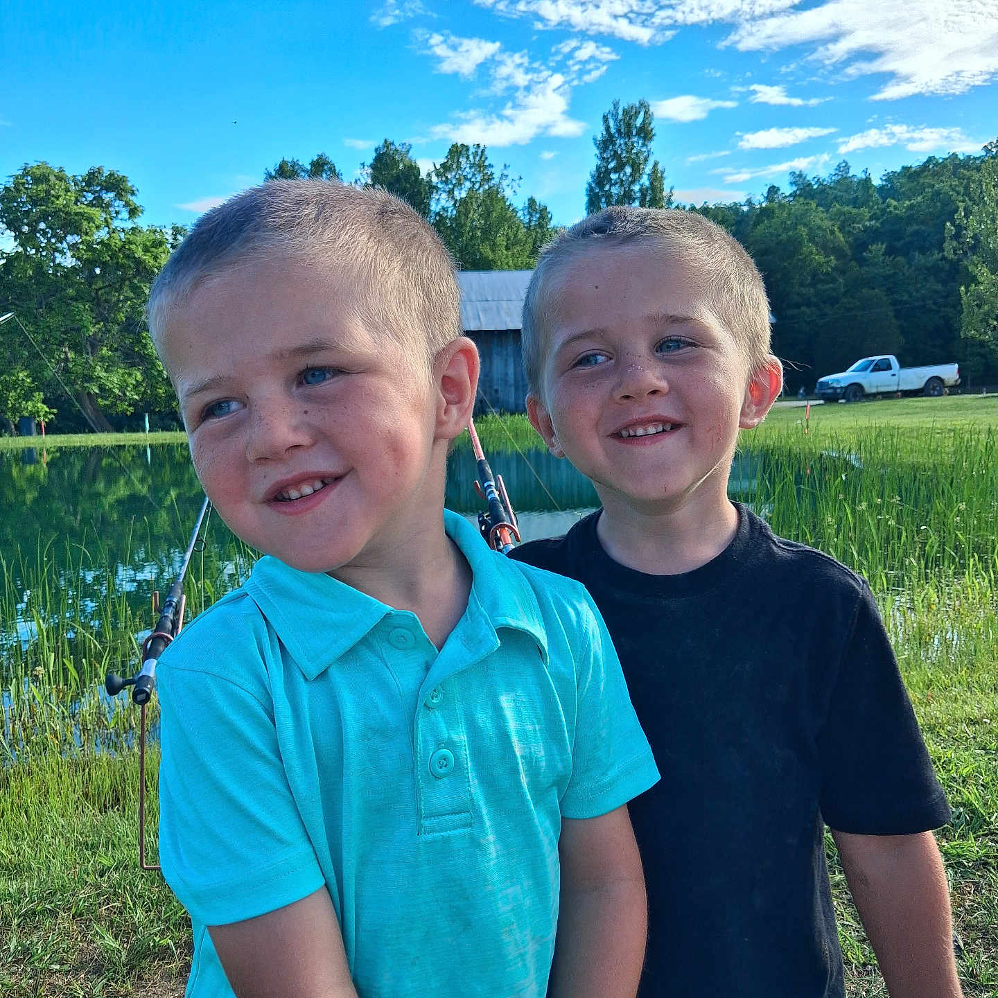 Hunter And Preston joined the competition — help win amazing prizes! child, boys, smiling, outdoor, fishing, pond, grass, trees, sky, clouds, blue_shirt, black_shirt, short_hair, nature, sunny, playful, happy, greenery, truck, barn