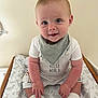 Freddie is registered to the contest to win money with this photo: baby, child, smiling, blue_eyes, bib, socks, sitting, cute, infant, face, clothing, patterned_bedding, indoor, portrait, happy, person, young_child, light_skin, short_hair, white_clothing