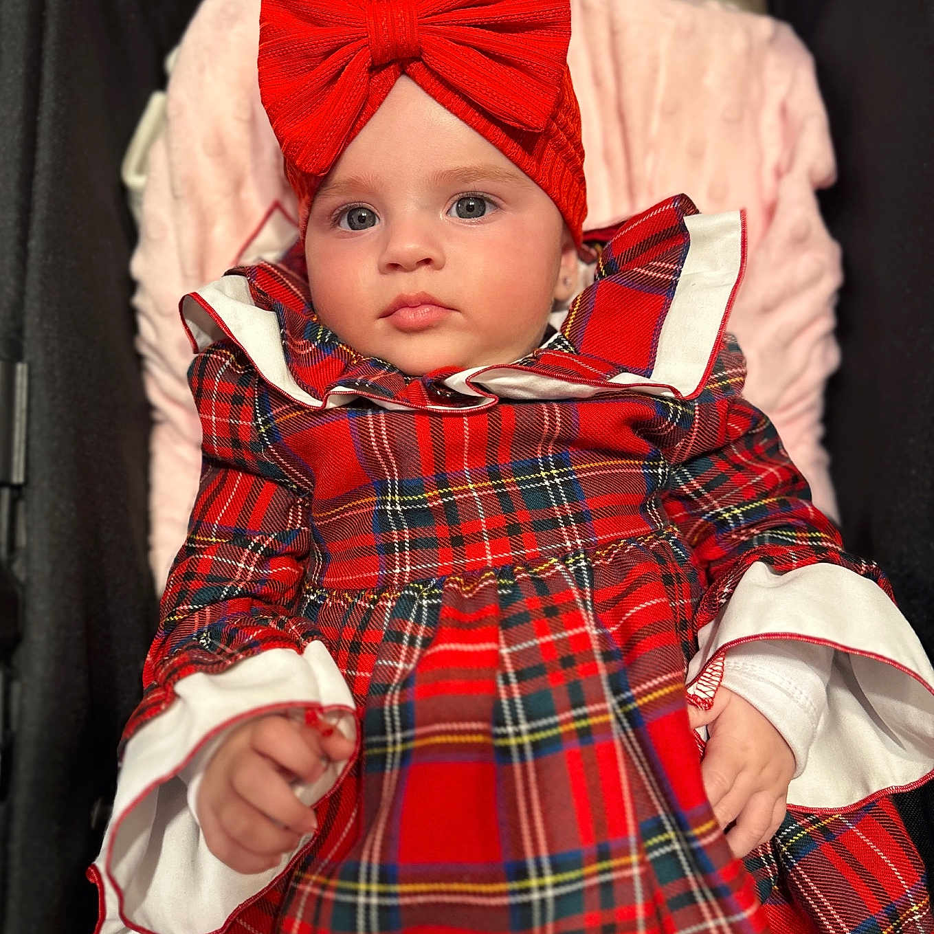 Sophia is registered to the contest to win money with this photo: baby, blanket, child, clothing, cute, dress, expression, fabric, face, hands, headband, indoors, infant, pink, plaid, portrait, red_bow, soft, stroller, young