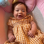 Londyn is registered to the contest to win money with this photo: baby, smiling, child, dress, yellow_checkered, pink_baby_seat, plush_toys, cloud, moon, star, happy, infant, cute, indoors, portrait, young_child, baby_clothing, comfort, cushion, playful
