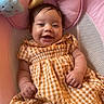 baby, smiling, child, dress, yellow_checkered, pink_baby_seat, plush_toys, cloud, moon, star, happy, infant, cute, indoors, portrait, young_child, baby_clothing, comfort, cushion, playful