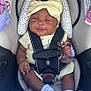 baby, car_seat, headband, pacifier, socks, infant, child, smiling, straps, seat_belt, clothing, cute, sitting, indoors, child_safety, person, toddler, baby_toy, fabric, accessory