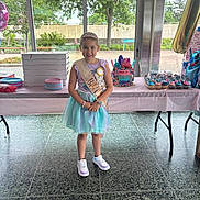 Evelyn joined the competition — help win amazing prizes! balloons, birthday, cake, celebration, child, cupcakes, decorations, dress, floor, food, indoor, party, person, sash, shoes, smile, table, tiara, trees, window