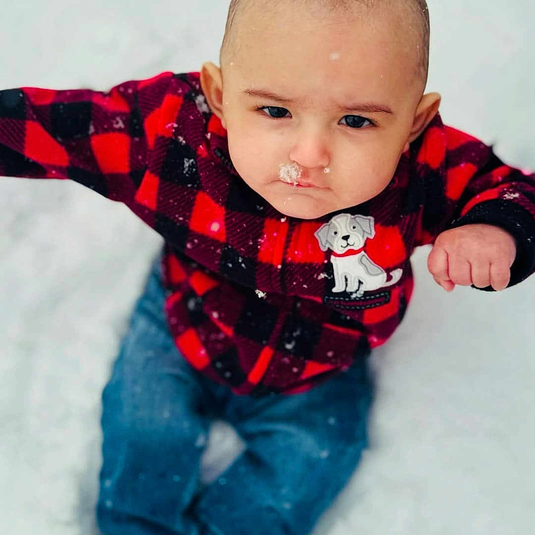 Micah is registered to the contest to win money with this photo: baby, checkered, child, clothing, cold, cute, determined, dog_patch, expression, face, frost, jeans, nose, outdoor, portrait, red_jacket, sitting, snow, snowflakes, winter
