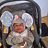 Princeton is registered to the contest to win money with this photo: baby, infant, child, car_seat, elephant_costume, elephant_hood, gray_clothing, pink_trunk, polka_dots, smiling, happy, face, portrait, indoor, floor, wooden_floor, yellow_toy, stroller, sitting, cozy