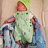 Joseph is registered to the contest to win money with this photo: newborn, baby, sleeping, infant, portrait, crib, blanket, hat, green, striped, romper, overalls, stuffed_animal, nursery, cozy, lying_down, peaceful, indoor, cuddled, textile