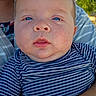 adorable, adult_arm, baby, background, blue_eyes, child, close_up, face, greenery, held, infant, navy_blue, outdoor, photography, portrait, serious_expression, striped_clothing, sunlight, white_stripes, wide_eyed