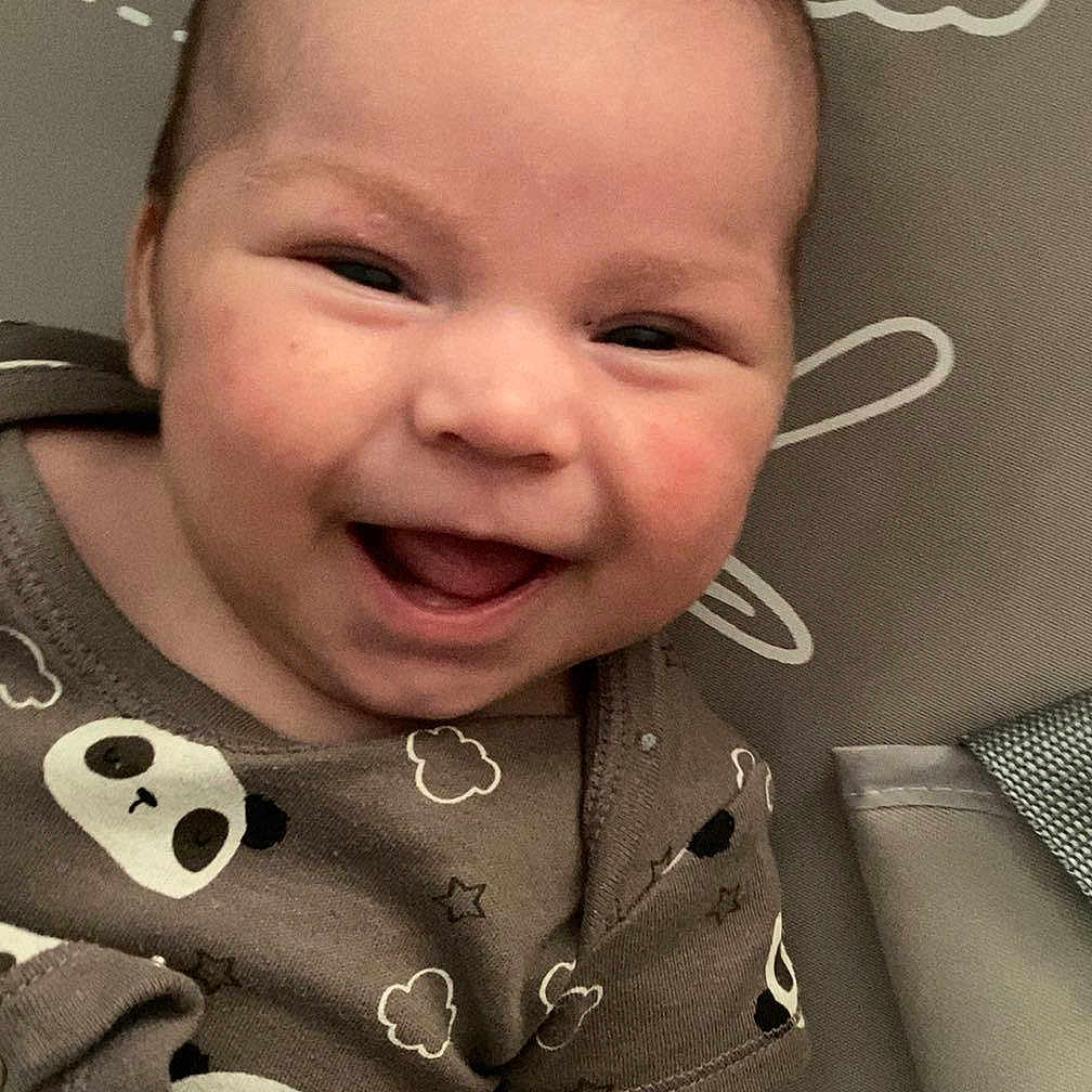 Hunter is registered to the contest to win money with this photo: arm, baby, cheeks, child, clothing, clouds, cute, eyes, face, happy, head, infant, lying_down, mouth, panda_print, patterned_background, skin, smiling, stars, toddler