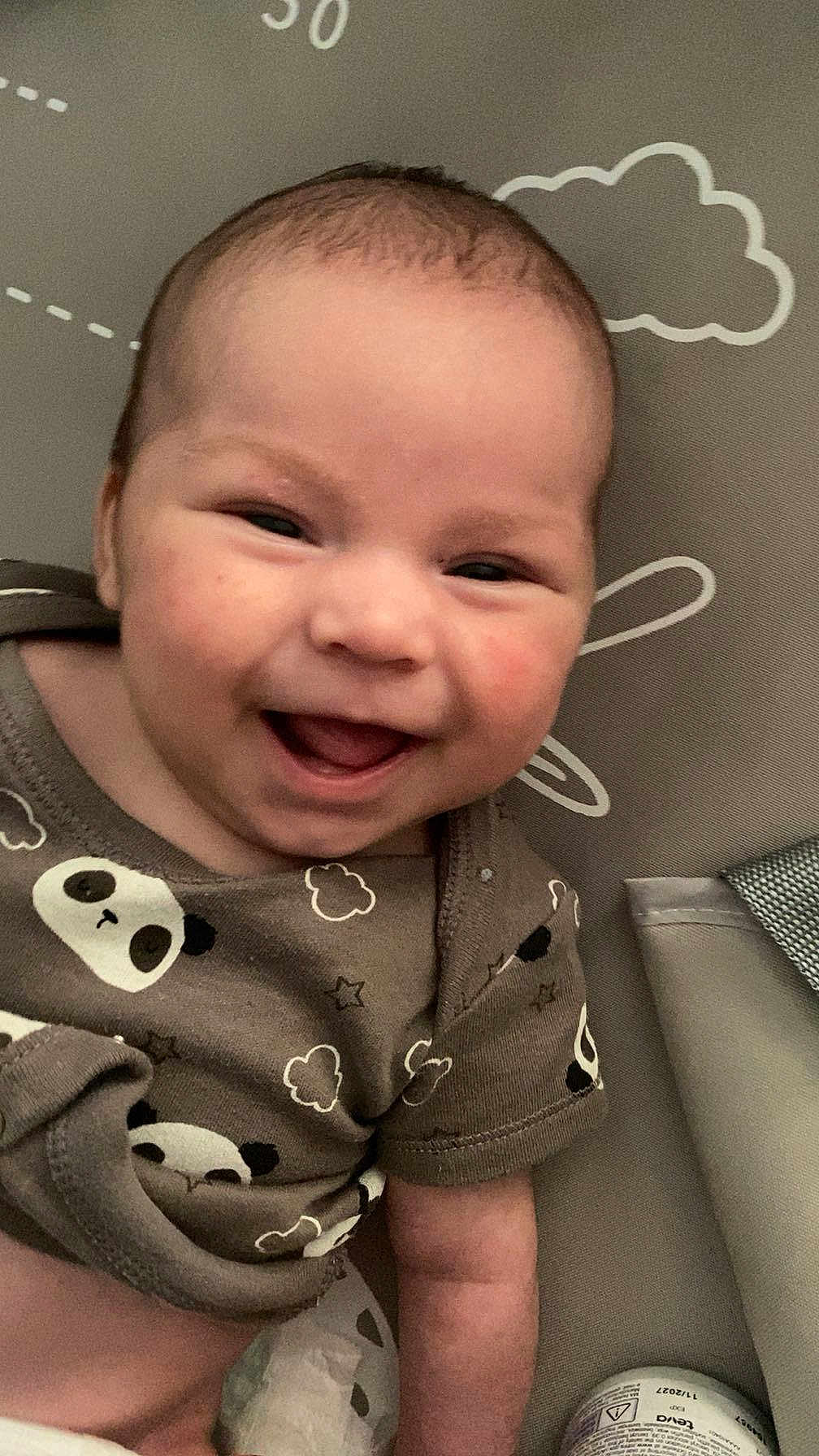 Hunter is registered to the contest to win money with this photo: baby, smiling, infant, face, clothing, panda_print, happy, cute, lying_down, patterned_background, clouds, stars, child, skin, arm, head, eyes, mouth, cheeks, toddler