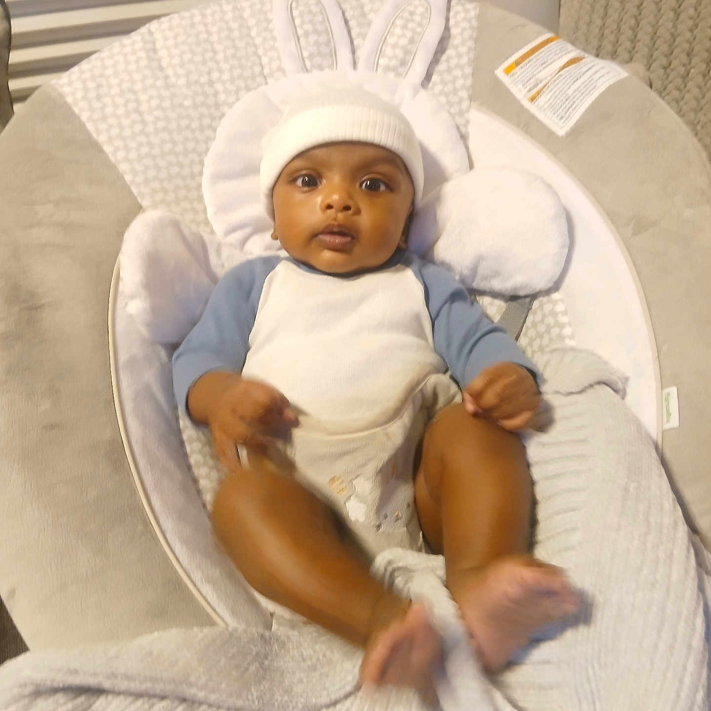 Kai is registered to the contest to win money with this photo: baby, blanket, bonnet, cap, clothing, crib, cushion, face, furniture, happy, hat, head, homedecor, infantbed, newborn, person, photography, portrait, sitting, smile