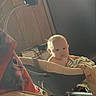 Asher joined the competition — help win amazing prizes! baby, child, infant, stroller, sitting, face, portrait, indoor, blanket, clothing, furniture, home, cozy, curious, looking_at_camera, soft_lighting, adult_partial, fabric, household, photography