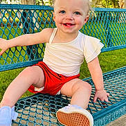 Nikkole joined the competition — help win amazing prizes! bench, blue_eyes, casual_clothing, child, cute, grass, greenery, happy, metal_bench, outdoor, park, red_bow, red_shorts, shoe, sitting, smile, sunlight, toddler, tree, white_shirt