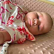Paizleigh is registered to the contest to win money with this photo: baby, infant, face, blanket, clothing, pink, red, white, pattern, beads, bracelet, arm, skin, portrait, lying_down, closeup, soft_texture, cute, child, young